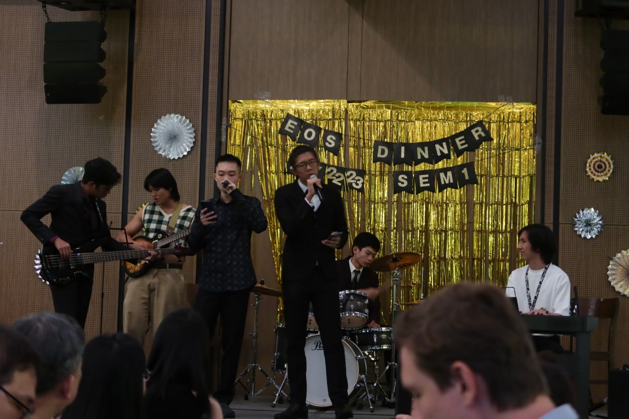 Shan Yuxuan singing with a band at an end-of-semester dinner